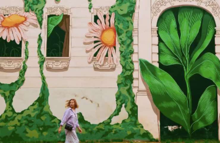 Donna cammina in prossimità di un murales floreale in Polonia